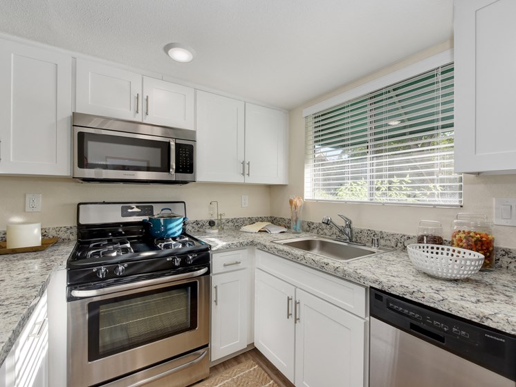 Kitchen with Granite Countertops, White Cabinets, Oven and Microwave